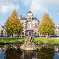 Edificio histórico rodeado de árboles otoñales y un estanque, ubicado cerca de Akkrum, Frisia, Países Bajos.