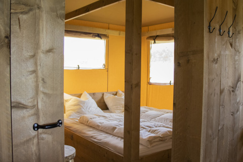 Chambre douillette avec lit double dans une Luxe Safaritent au Familievakantiepark Krieghuusbelten, Pays-Bas.