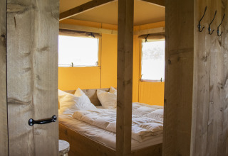 Camera accogliente con letto matrimoniale in una Luxe Safaritent al Familievakantiepark Krieghuusbelten, Paesi Bassi.