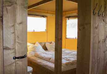 Indvendigt billede af et hyggeligt soveområde med dobbeltseng i en Luxe Safaritent på Krieghuusbelten.