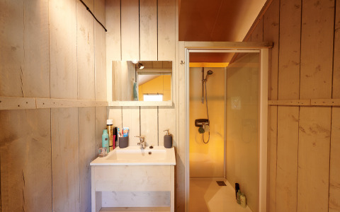 Bagno nella Luxe Safaritent al Familievakantiepark Krieghuusbelten con cabina doccia e pareti in legno.