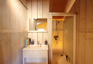 Salle de bain dans la Luxe Safaritent au Familievakantiepark Krieghuusbelten avec douche et lavabo.