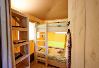 Vue intérieure d'une chambre confortable avec lits superposés et étagères dans une tente safari aux Pays-Bas.