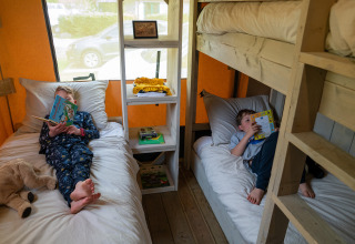 Twee kinderen lezen boeken op bedden in een Rangerlodge safaritent bij Familievakantiepark Krieghuusbelten.