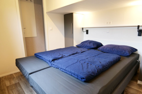 Lit moderne avec draps et oreillers bleus à Waterlodge, Familievakantiepark Krieghuusbelten, Pays-Bas.