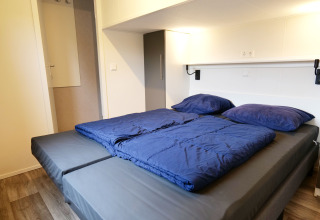 Lit moderne avec draps et oreillers bleus à Waterlodge, Familievakantiepark Krieghuusbelten, Pays-Bas.