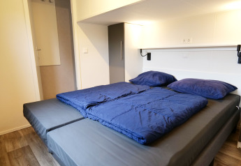 Lit moderne avec draps et oreillers bleus à Waterlodge, Familievakantiepark Krieghuusbelten, Pays-Bas.