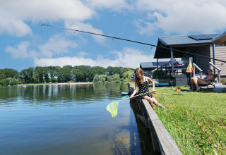 Fille pêchant au bord du lac près d'une Waterlodge au Familievakantiepark Krieghuusbelten, Pays-Bas, femme assise.