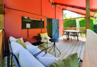 Overdækket terrasse på Wander Lodge i Vakantiepark Delftse Hout, med sofaer, borde og udsigt til haven.