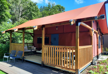 Vista esterna di Wander Lodge al Vakantiepark Delftse Hout nei Paesi Bassi, con veranda e area salotto.