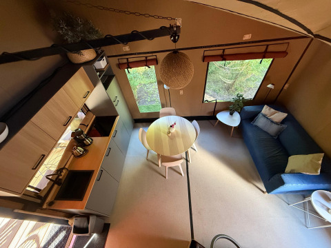 Modern lodge-interieur met keuken, ronde eettafel en zetel in Wander Lodge te Vakantiepark Delftse Hout, Nederland.