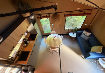 Interno lodge moderno con cucina, tavolo rotondo e divano al Wander Lodge nel Vakantiepark Delftse Hout, Paesi Bassi.