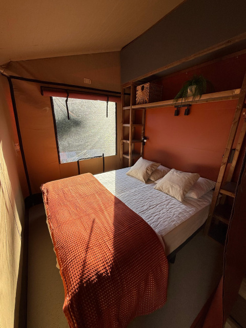 Camera da letto presso Wander Lodge nel Vakantiepark Delftse Hout, Paesi Bassi, illuminata dal sole.