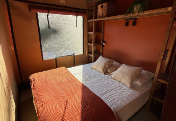Soveværelse i Wander Lodge på Vakantiepark Delftse Hout, Nederlandene, med sollys gennem vindue.