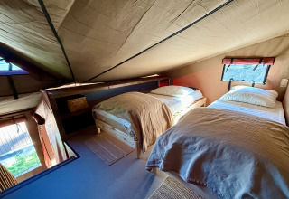 Cozy twin bedroom with slanted ceiling at Wander Lodge in Vakantiepark Delftse Hout, Netherlands.