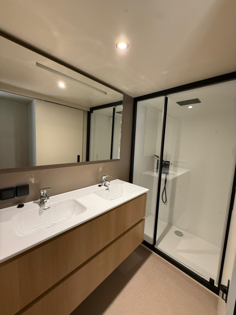 Moderne badkamer met dubbele lavabo en douche in de Wander Lodge, Vakantiepark Delftse Hout, Nederland.