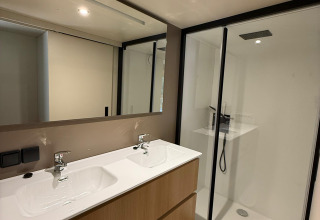 Baño moderno con doble lavabo y ducha de vidrio en Wander Lodge, Vakantiepark Delftse Hout, Países Bajos.