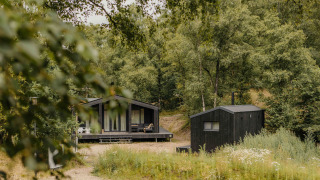 Afbeelding van The Hills tiny house met hottub en sauna, omringd door een groene, bosrijke natuur.