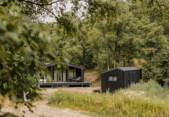 Foto de la tiny house The Hills con bañera de hidromasaje y sauna en un entorno boscoso y verde.