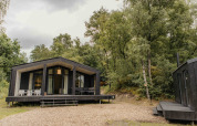 Zwart tiny house met veranda in een bos bij Wilsumer Berge, Duitsland, The Hills met hot tub en sauna.