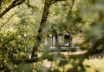 Pequeña casa negra The Hills con bañera de hidromasaje y sauna, entre árboles en Wilsumer Berge, Alemania.