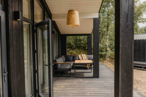 Moderne overdekte veranda met zitbank en tafel aan tiny house The Hills in Wilsumer Berge, Duitsland.
