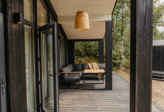 Moderne overdekte veranda met zitbank en tafel aan tiny house The Hills in Wilsumer Berge, Duitsland.