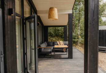 Porche cubierto moderno con sofá y mesa en la tiny house The Hills, Wilsumer Berge, Alemania.