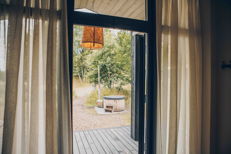 Vista desde una tiny house hacia el jacuzzi exterior en Wilsumer Berge, Alemania, puerta abierta.
