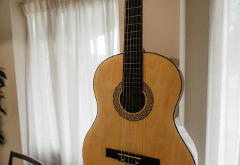 Guitarra acústica en una habitación luminosa con cortinas en The Hills tiny house en Wilsumer Berge, Alemania.