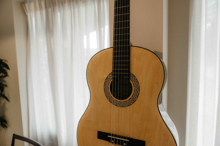 Guitarra acústica en una habitación luminosa con cortinas en The Hills tiny house en Wilsumer Berge, Alemania.