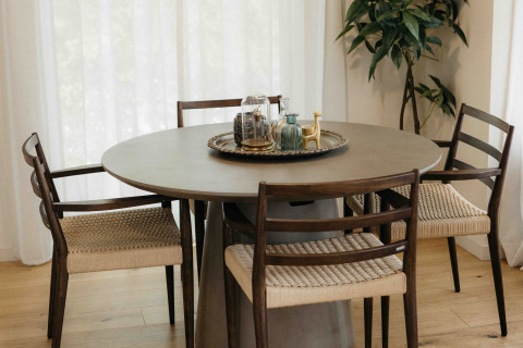 Ronde eettafel met vier stoelen, stijlvol dienblad, lichte houten vloer en hoge witte gordijnen.