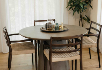Ronde eettafel met vier stoelen, stijlvol dienblad, lichte houten vloer en hoge witte gordijnen.