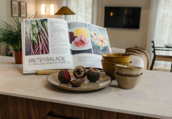Kookboek met recept voor bietensalade open in een glamping keuken, met kommen en rauwe bieten.