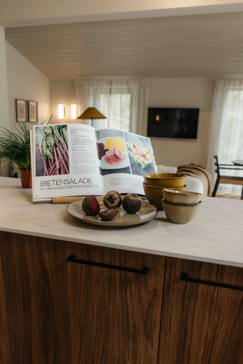 Libro de cocina abierto con receta de ensalada de remolacha en una cocina glamping con cuencos y remolachas.