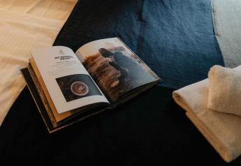 Libro abierto y toallas dobladas sobre una cama en un alojamiento glamping con un ambiente acogedor y relajante.