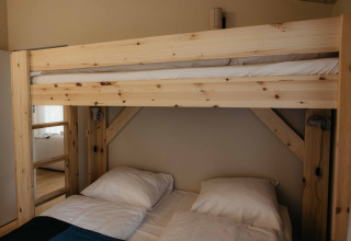 Houten stapelbed met beddengoed in The Hills tiny house met jacuzzi en sauna in Wilsumer Berge, Duitsland.