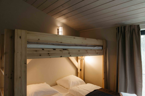 Knusse slaapkamer met houten stapelbedden en sfeerverlichting in een tiny house in Duitsland.