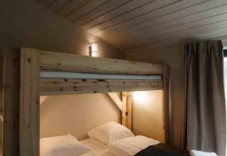 Knusse slaapkamer met houten stapelbedden en sfeerverlichting in een tiny house in Duitsland.