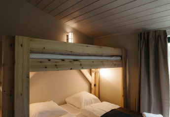 Dormitorio acogedor con literas de madera y luz suave en una tiny house en Wilsumer Berge, Alemania.