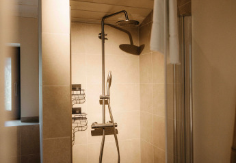 Imagen de una ducha moderna con cabezal de lluvia y paredes de azulejos en un alojamiento de glamping.