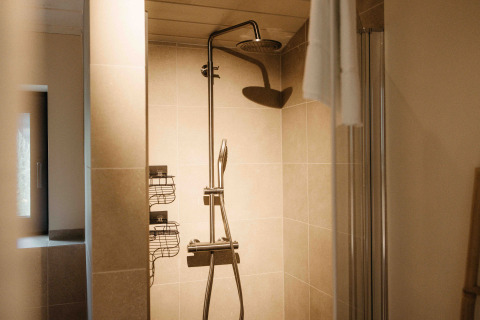 Imagen de una ducha moderna con cabezal de lluvia y paredes de azulejos en un alojamiento de glamping.