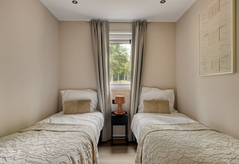 Slaapkamer met twee eenpersoonsbedden, nachtkastje en raam bij Heidehof 5 personen, Bospark Ede, Nederland.