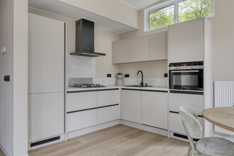 Modern light kitchen in Heidehof 5 personen lodge at Bospark Ede, Netherlands, with window and appliances.