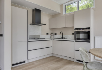 Moderne Küche im Heidehof 5 Personen-Lodge, Bospark Ede, Niederlande, mit hellen Schränken und Geräten.