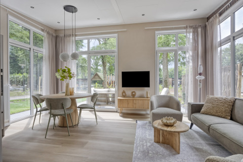 Salon moderne avec grandes fenêtres, coin repas et canapé dans le lodge Heidehof 5 personen à Bospark Ede, Pays-Bas.