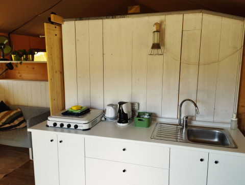 Keukenruimte in een safaritent met fornuis, gootsteen en koffiezetapparaat op Camping Suasa in Italië.