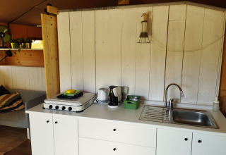 Keukenruimte in een safaritent met fornuis, gootsteen en koffiezetapparaat op Camping Suasa in Italië.