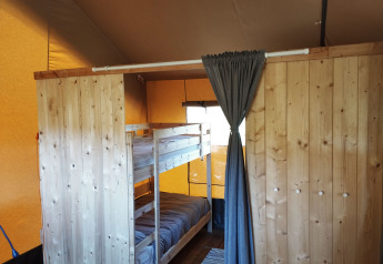 Binnenaanzicht van een safaritent met stapelbed en houten wand bij Camping Suasa in Italië.