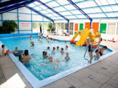 Niños jugando en una piscina cubierta con tobogán en el parque vacacional ’t Strandheem en Groningen, Países Bajos.